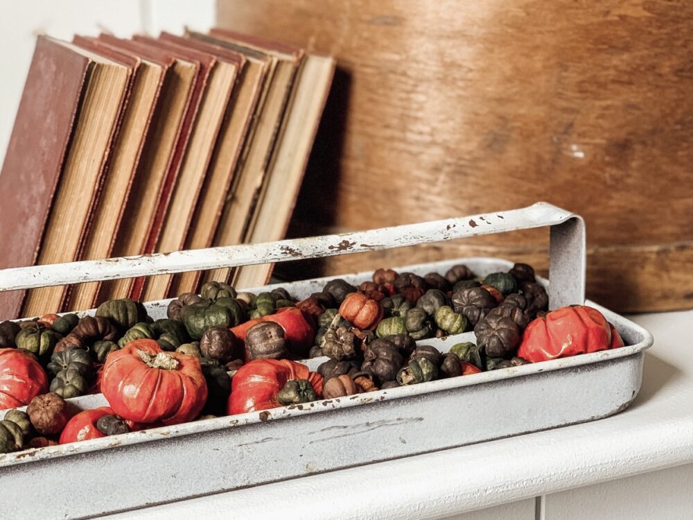 An old tool tray filled with fall potpourri beside antiuqe books.