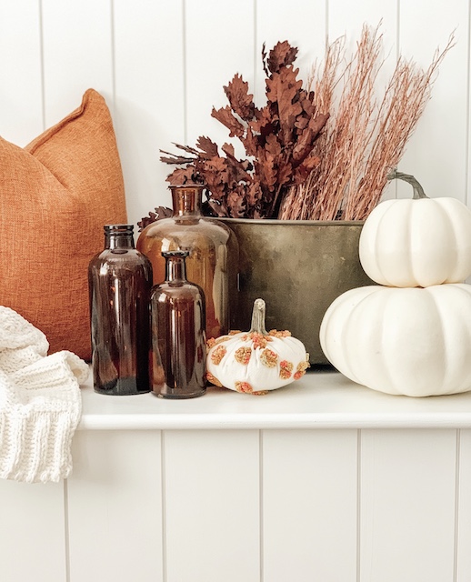 A bunch of fall items sitting on a bench.  