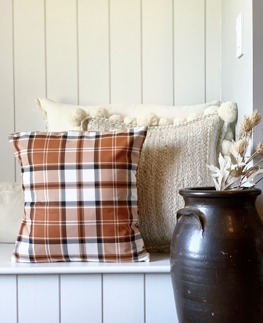A fall pillow sitting on a bench as decor