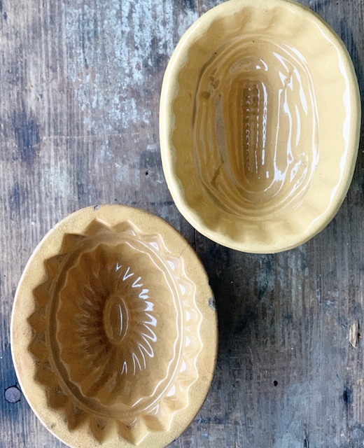 two antique yellowware molds sitting on a table outside waiting to be cleaned