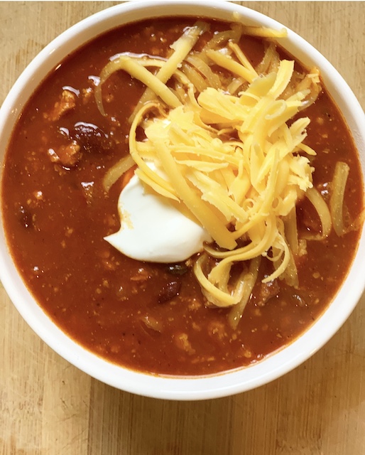 a huge bowl of chili with sour cream and cheese