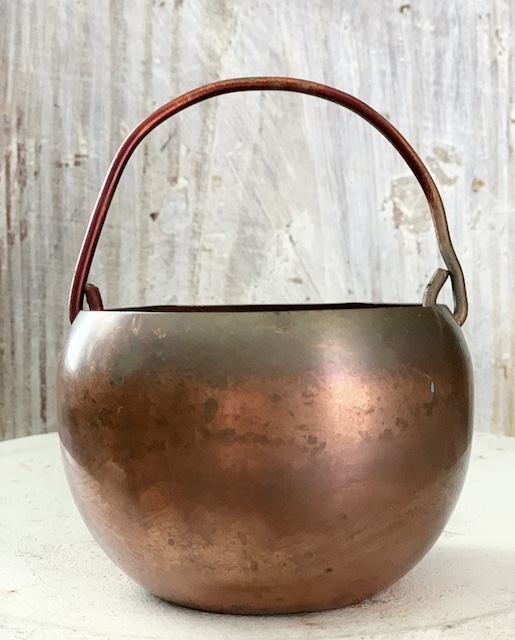 a tiny copper pot sitting on the table