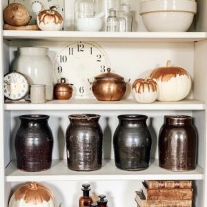A bookcase of vintage items and copper guilded pumkins.
