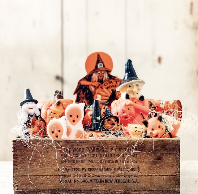 Many small pieces of vintage halloween decor sitting on a box as a display