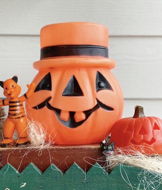 A vintage halloween blow mold pumpkin sitting on top of a shelf.