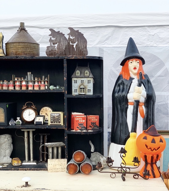 a witch and a pumpkin blow mold sitting on a table at a vintage market for sale.