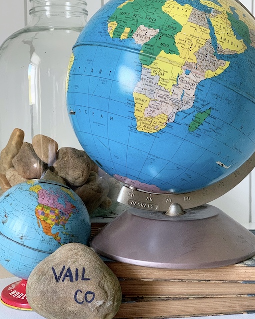 Two vintage globes and a stone sitting on a table