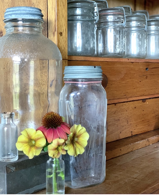 A row of mason jars with fresh flowers beside 