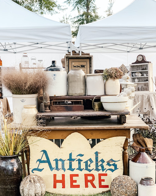 A farm table full of crocks as the main display at a vintage market