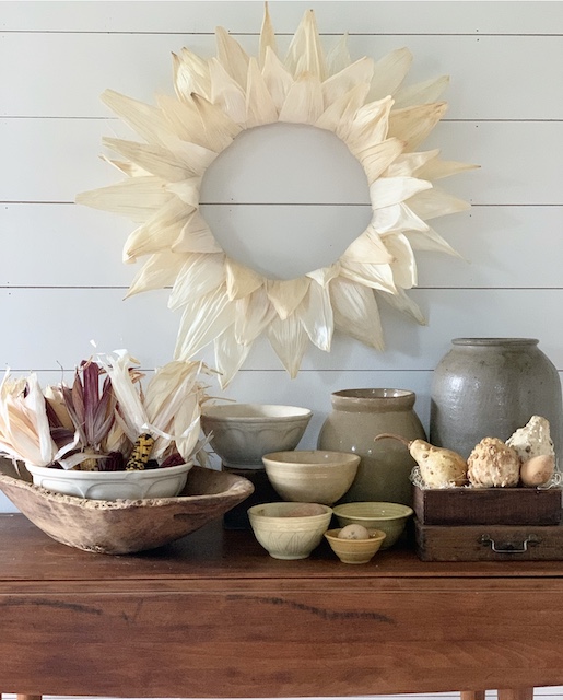 simple corn husk wreath displayed with bowls and crocks