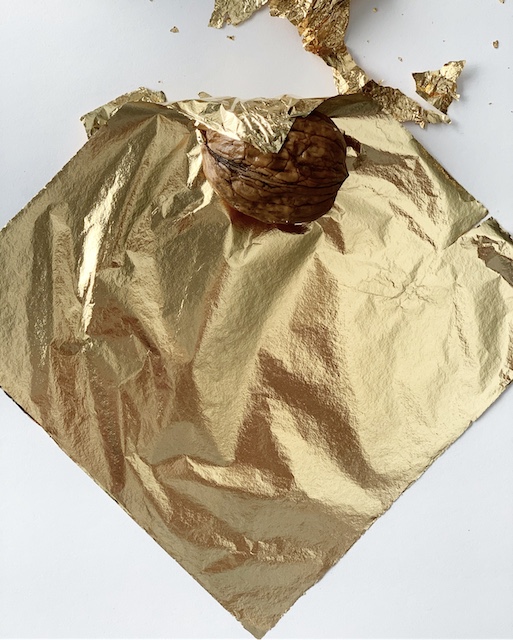 walnut half way wrapped in gold leaf