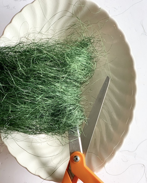 A mound of sisal over a bowl being trimmed