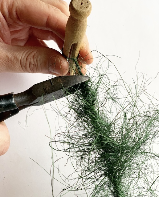 snipping the extra wire off of the top of a homemade bottle brush tree