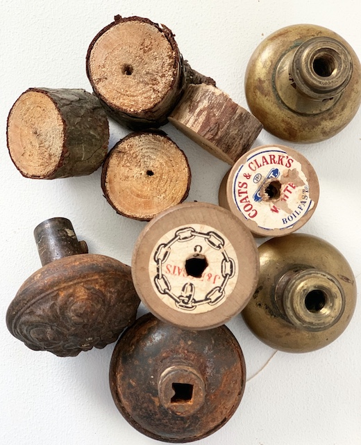a pile of doorknobs and spools of thread and pieces of wood