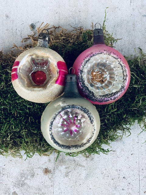 three ornaments sitting on moss