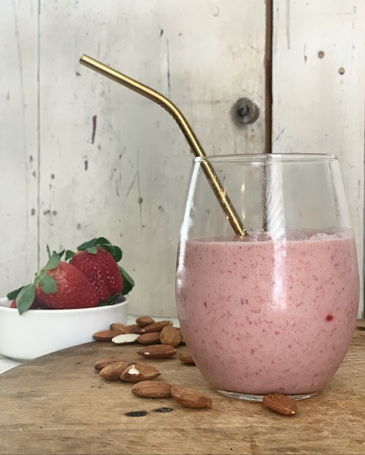 strawberries and almonds behind a glass of smoothie