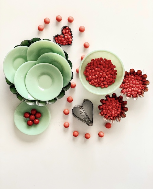 a stack of jadeite dishes filled with candy red hots for valentine decor