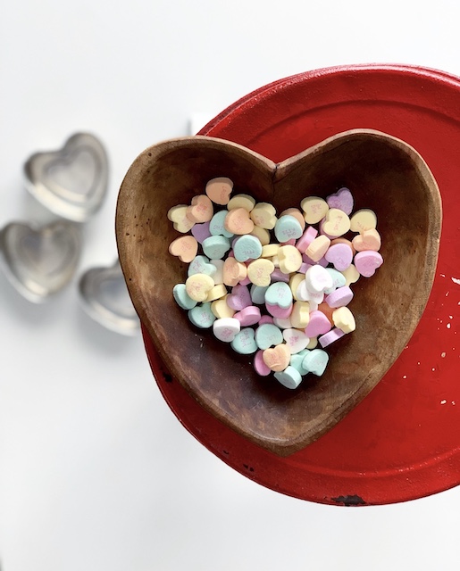 a wooden heart filled with candy hearts