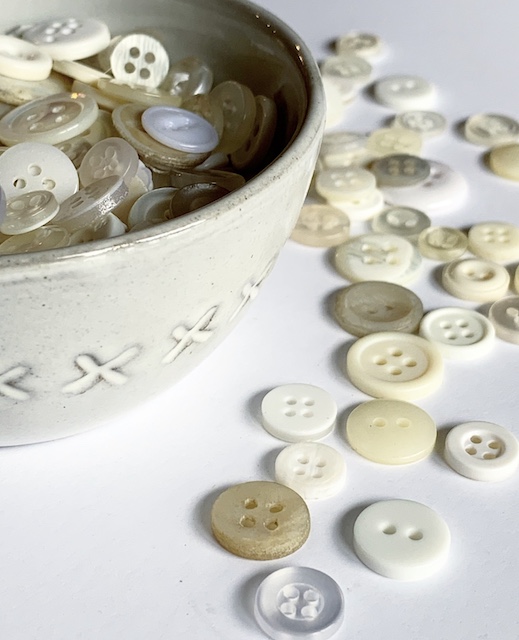 a bowl of buttons with some that have soilled out