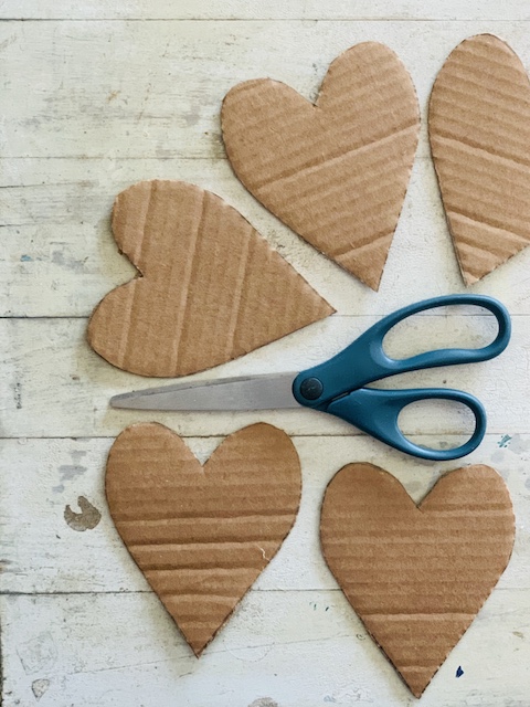 5 card board hearts cut out with a pair of scissors