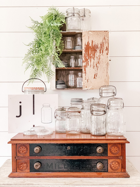 a bunch of old mason jars sitting on a spool cabinet
