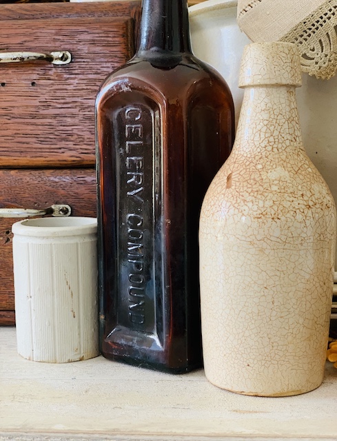 An old stoneware bottle and an amber bottle on a table