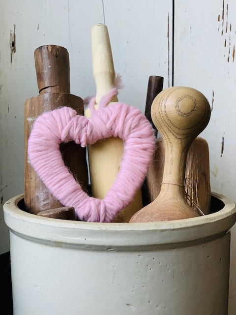 cozy yarn heart styled in a crock filled with kitchen utensils