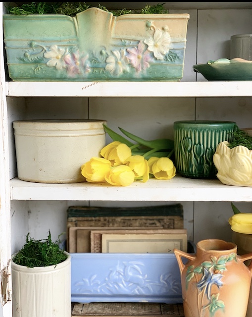 a mix of old planters on the same shelf