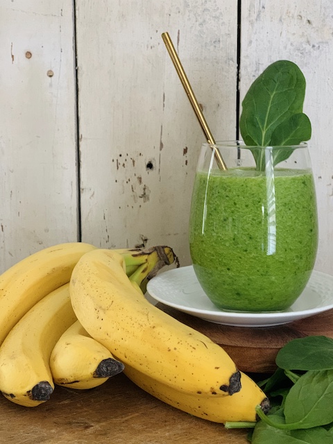 best green smoothie all mixed up next to bananas and spinach leaves
