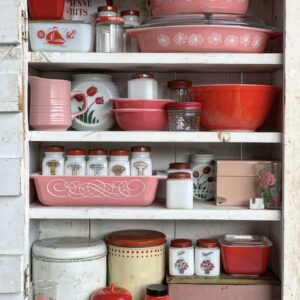 a mass of vintage pyrex and vintage kitchen on a shelf