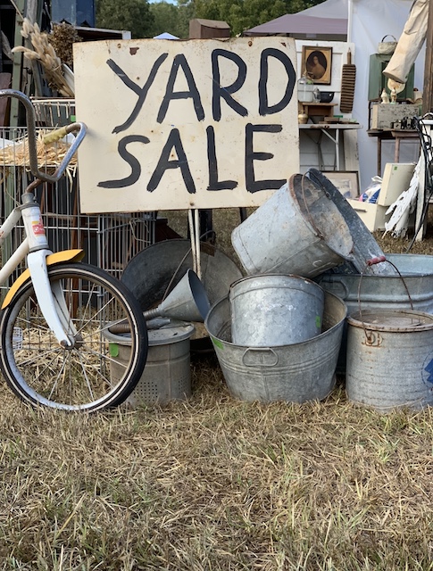 a yard sale sign in front of a lot of buckets