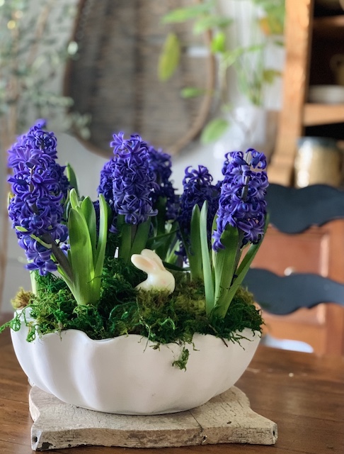 purple flowers in a bowl with a bunny sticking out.