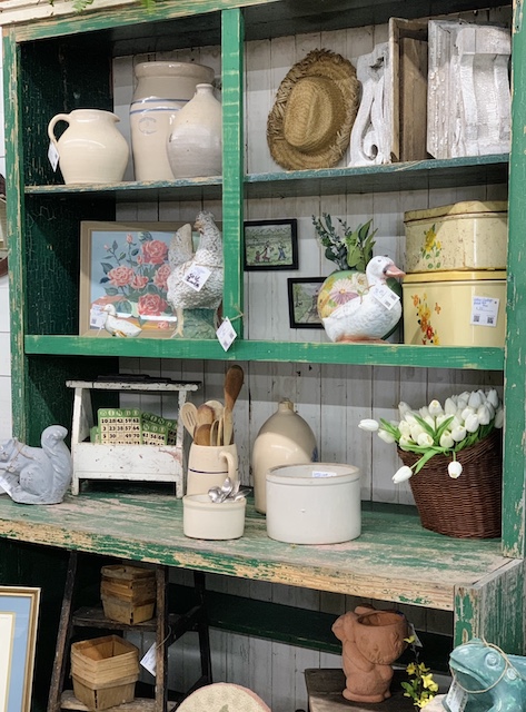 a set of green shelves full of antique and vintage finds
