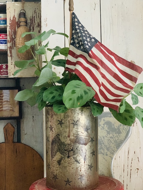 a flag tucked into an old can with a plant