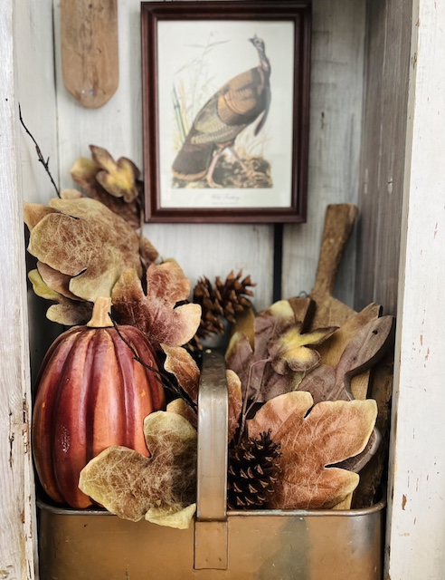 the bottom half of the cabinet decorated for fall