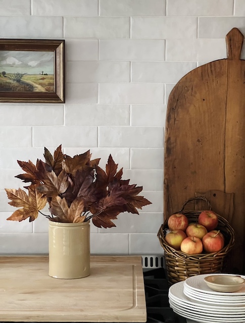 Kitchen Counter Fall Decor including a bread board and some stems